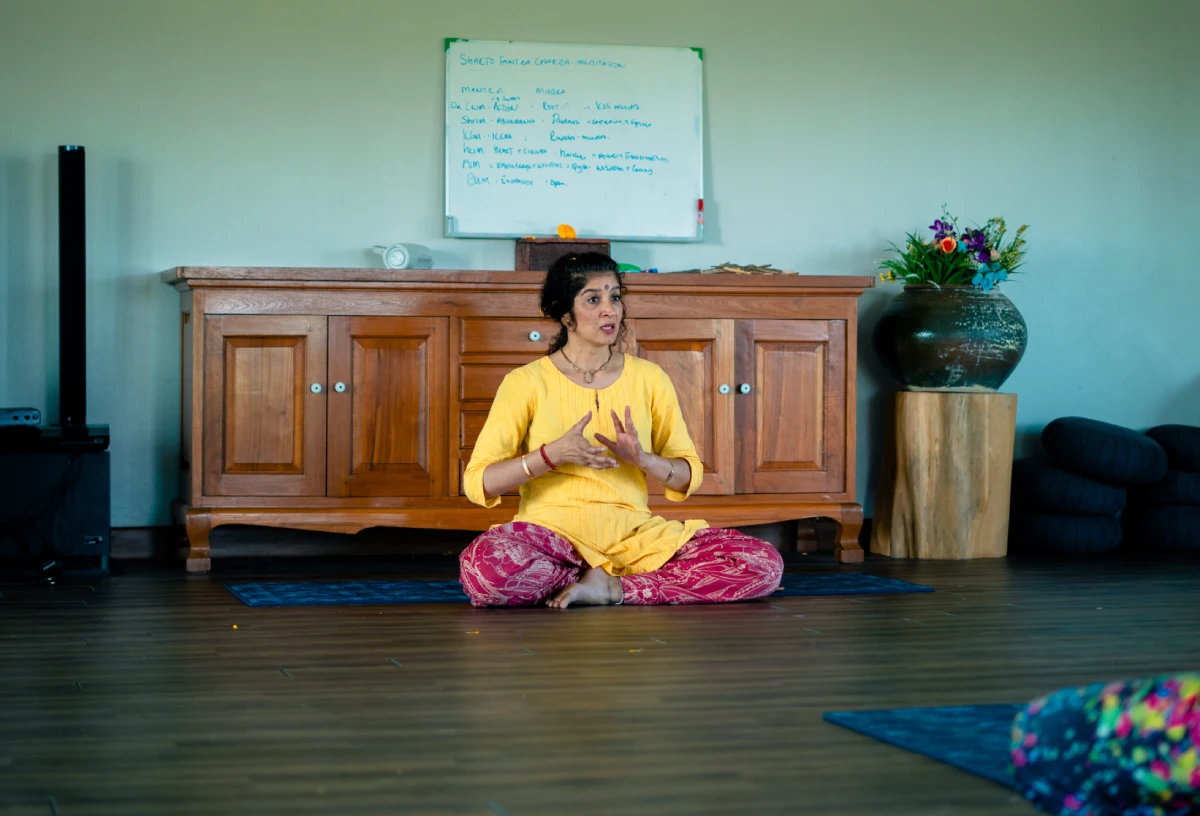 A teacher leading a seated class in the yoga hall