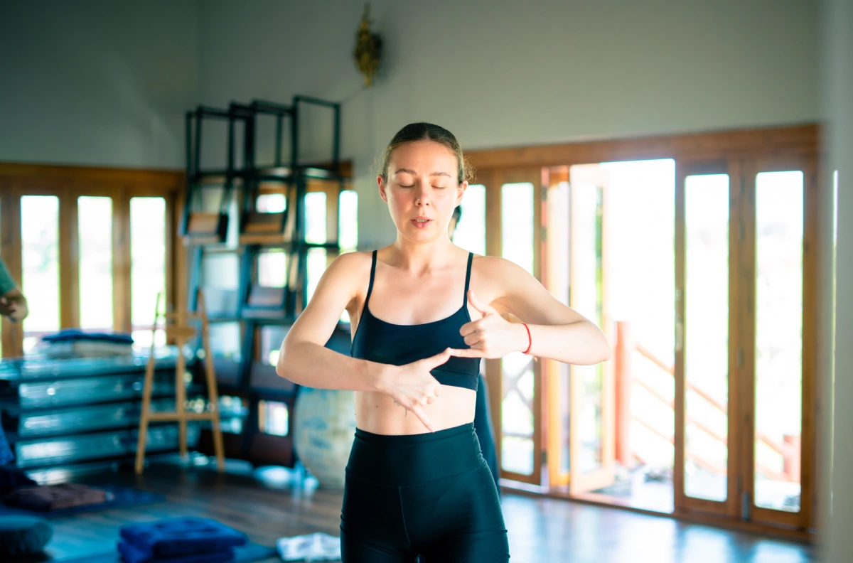 A student practising breathwork with hands at the navel in the yoga hall
