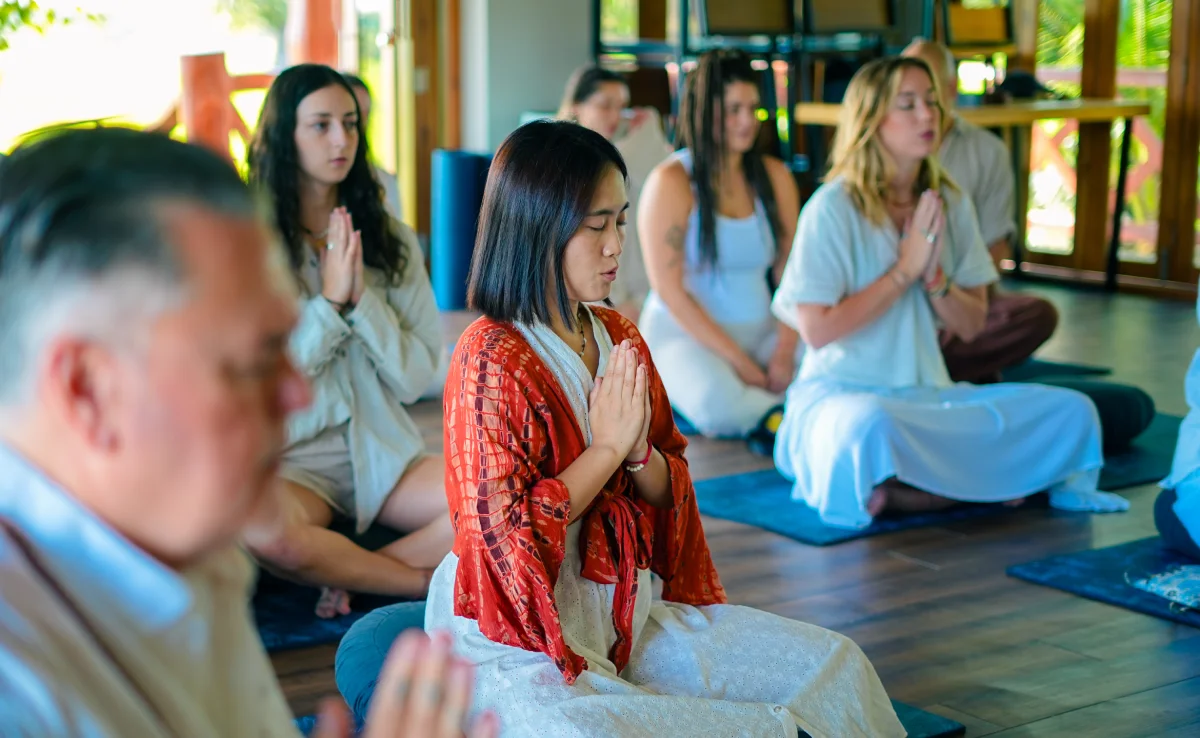 Students seated in prayer pose during a group meditation