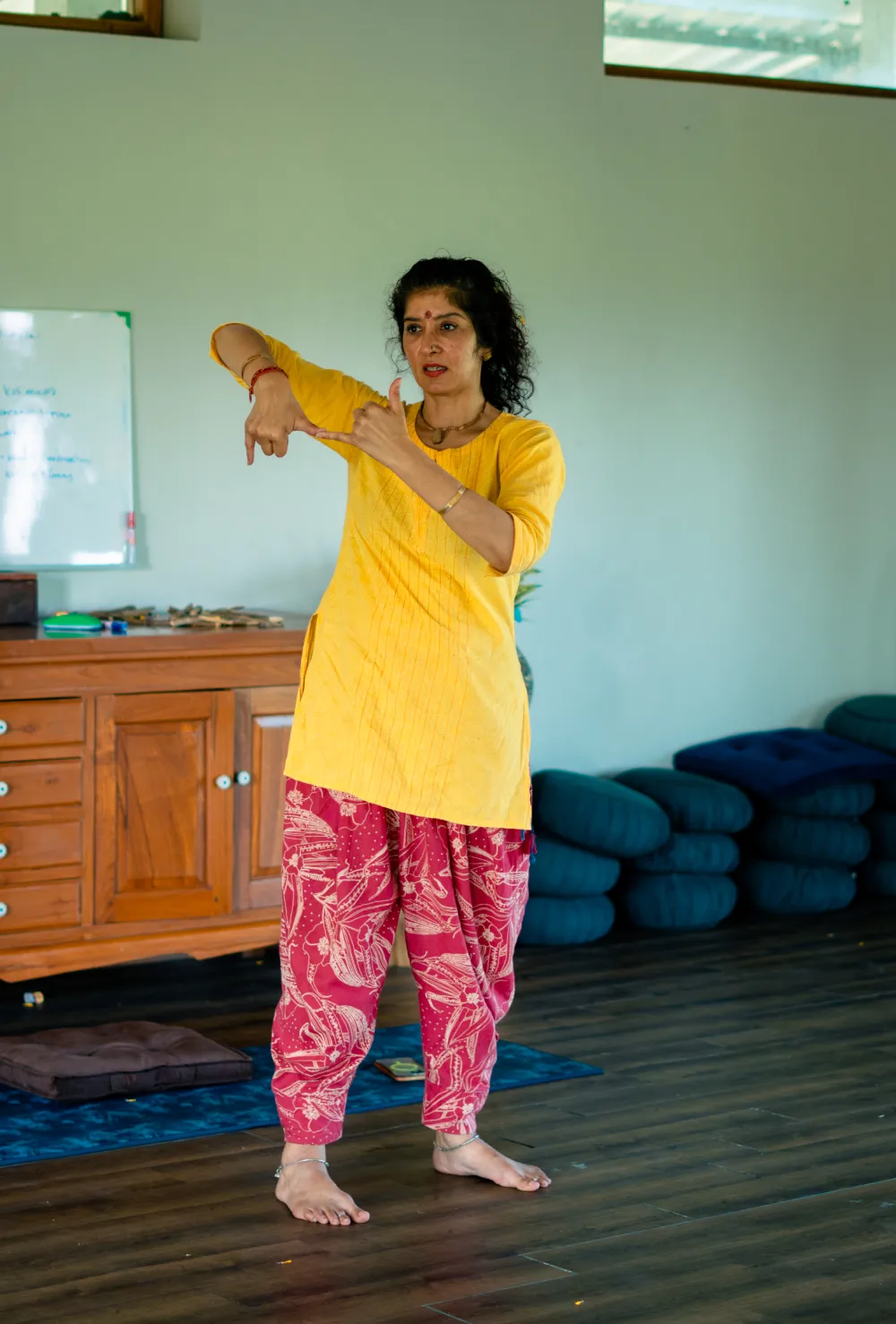 A teacher demonstrating a hand mudra in the yoga hall