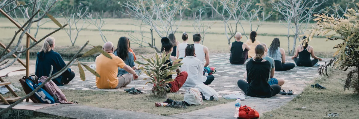 Residents sitting in group meditation on the lawn at the Chiang Mai campus
