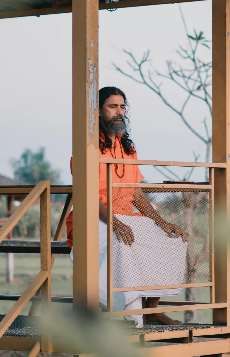A yogi meditating on the outdoor platform at dusk