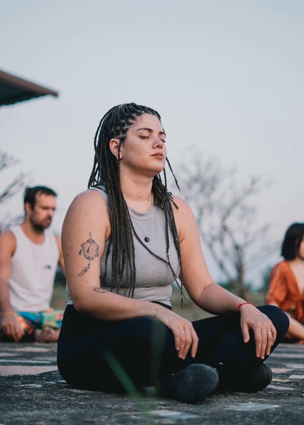 A woman meditating with eyes closed outdoors at dusk