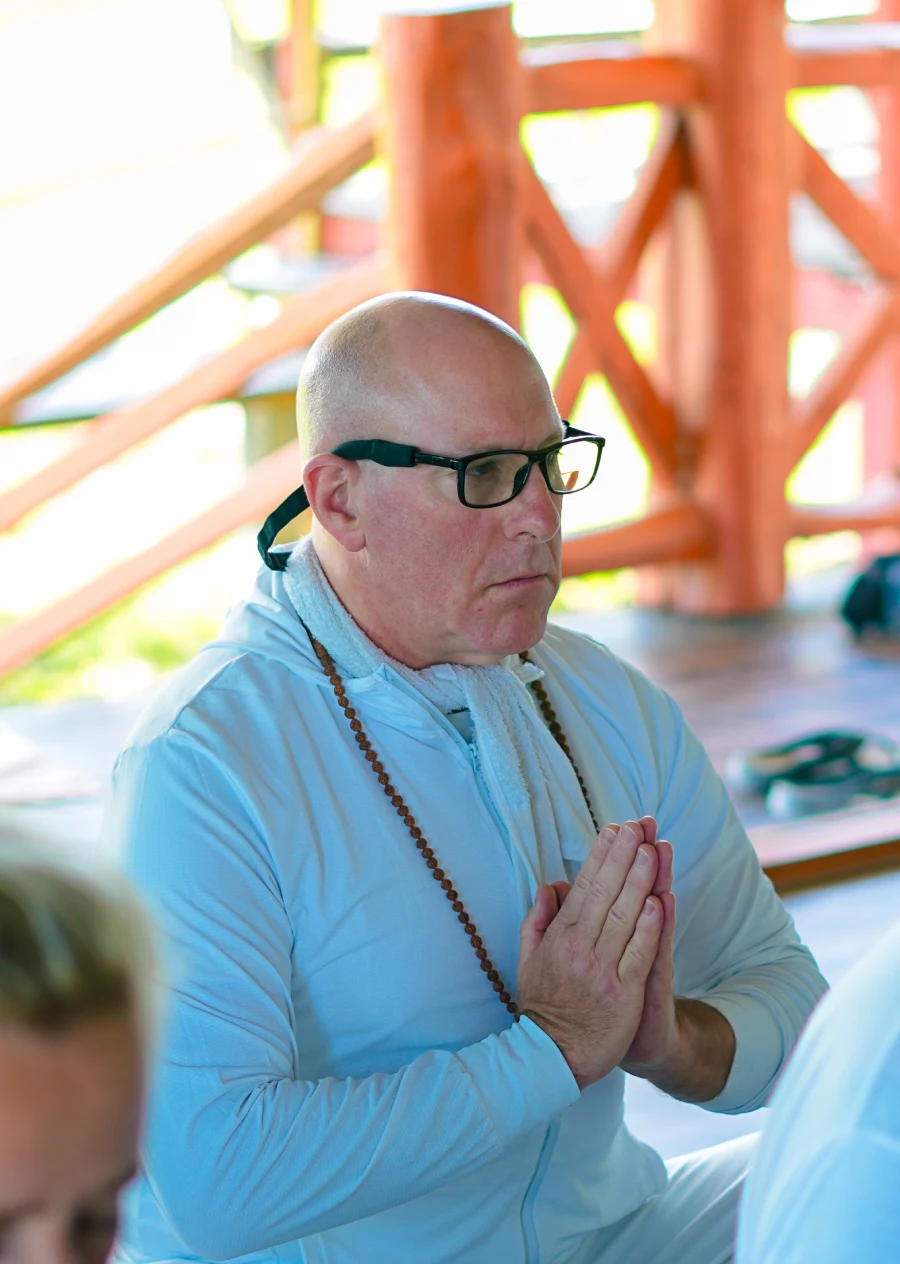 A retreat participant with folded hands and mala beads