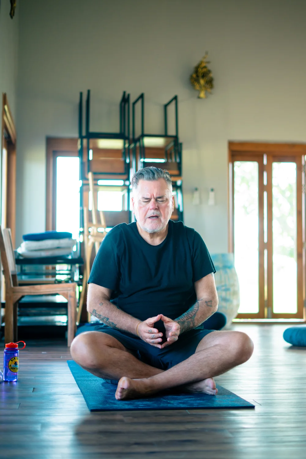 A senior guest meditating cross-legged in the yoga hall