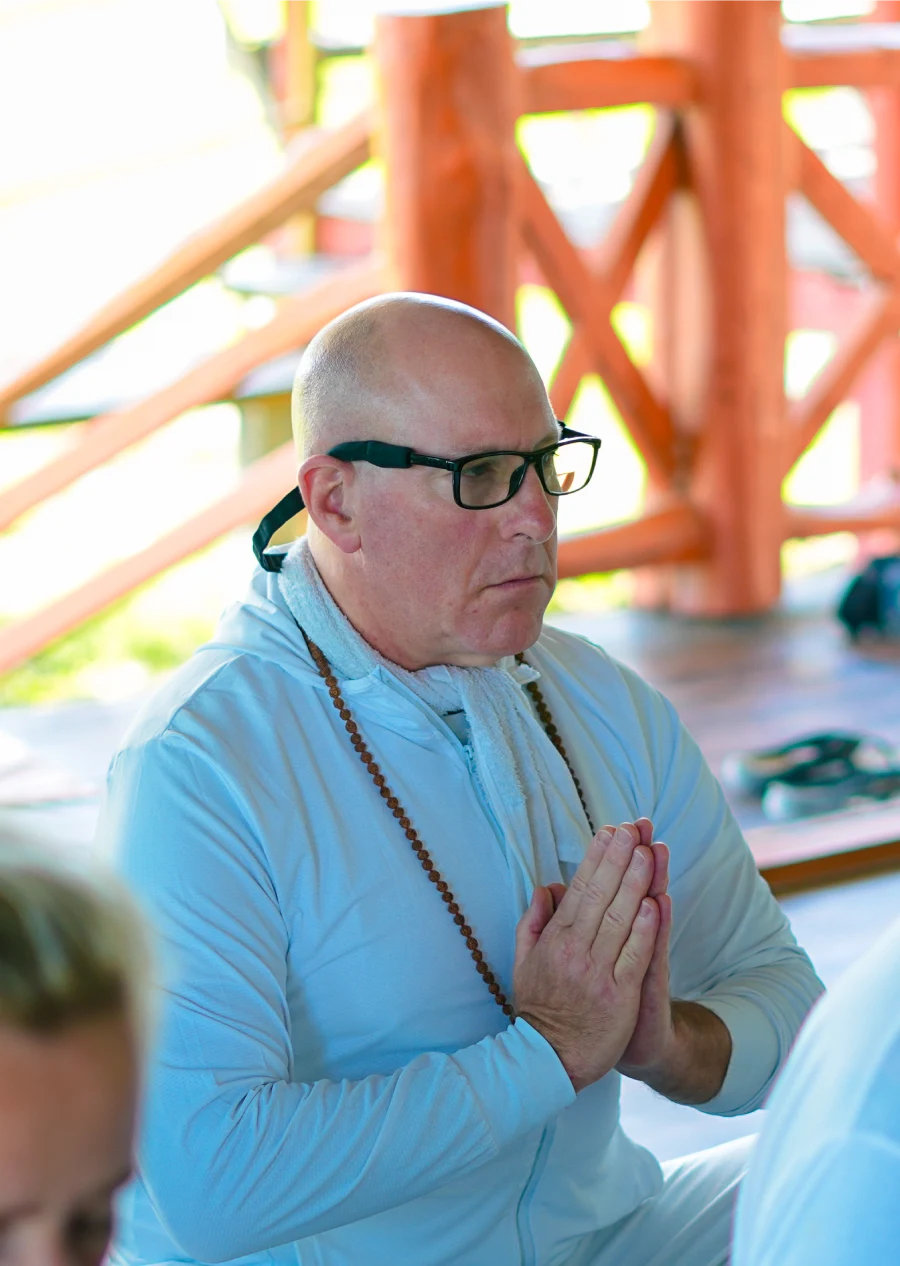 A guest with mala beads and folded hands