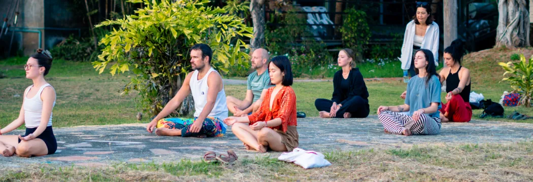 Retreat guests meditating on the lawn at the Chiang Mai campus