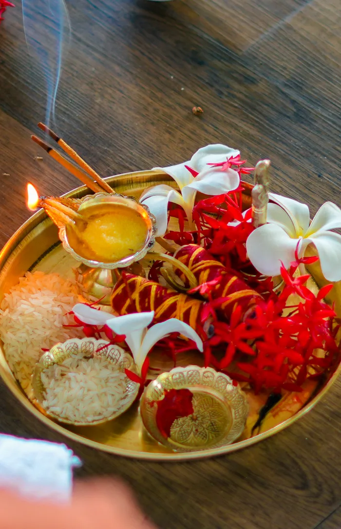 A puja plate with a ghee lamp, incense and flowers