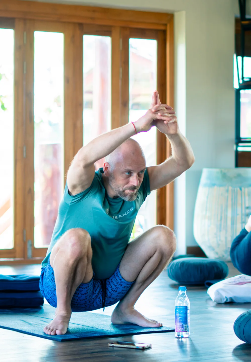 A guest in a squat with eagle arms in the yoga hall