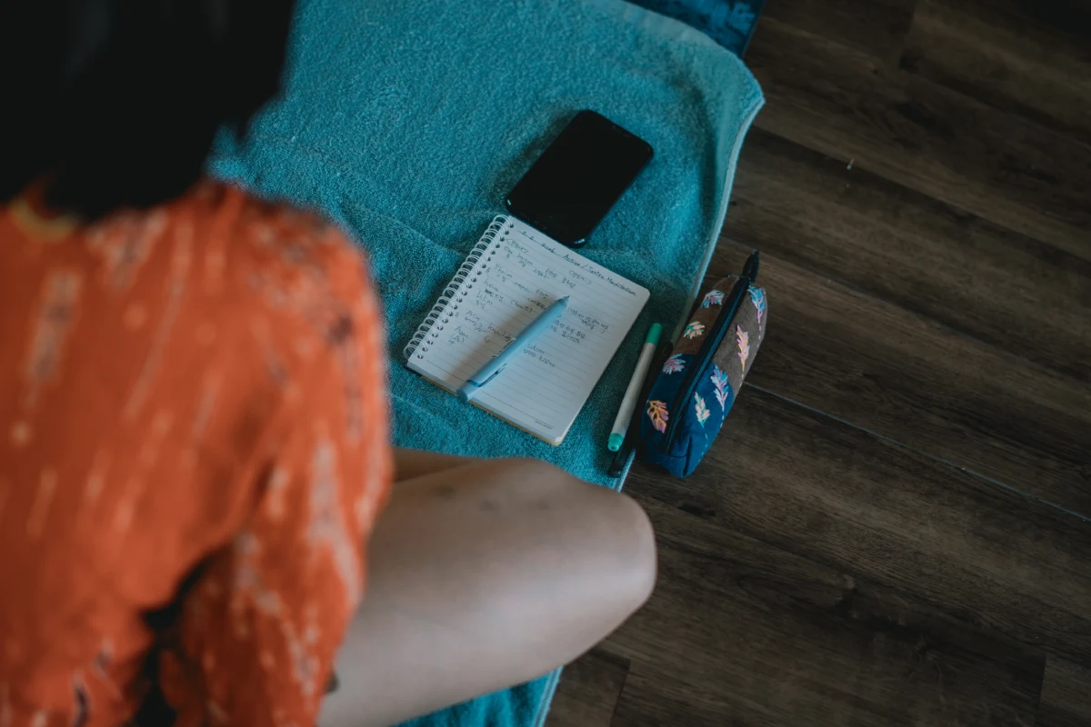 A student taking notes on a mat during a teacher training class