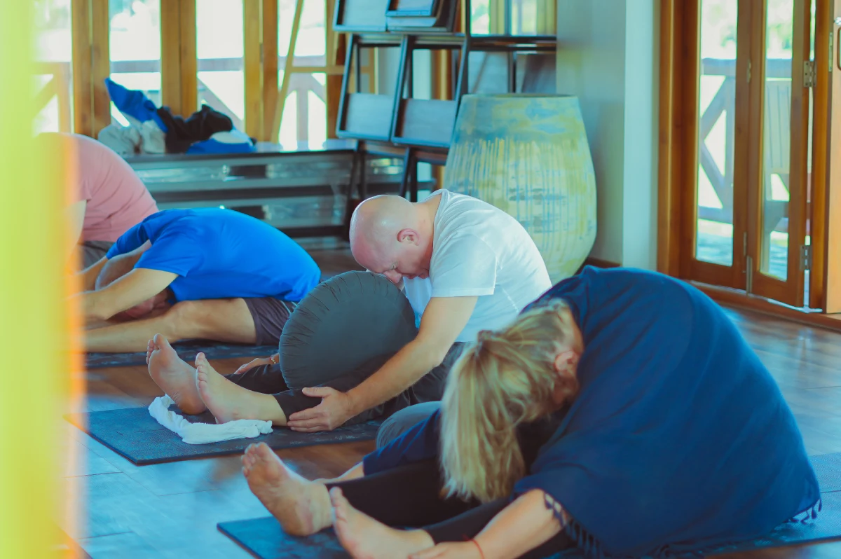 Students in a seated Yin forward fold with bolsters