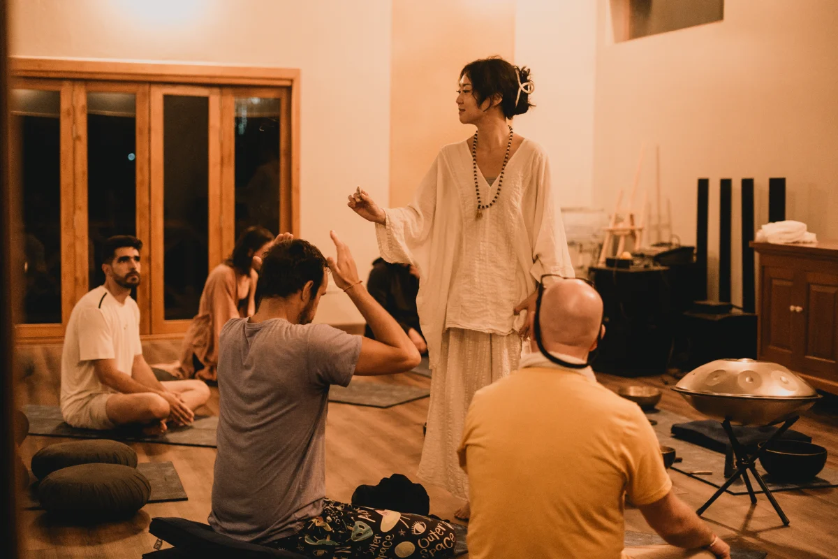 A teacher guiding students through a handpan sound session in the yoga hall