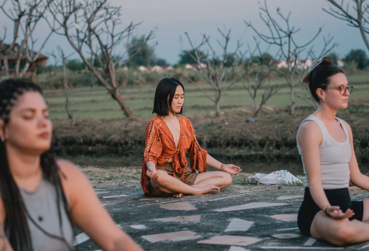 Students meditating cross-legged outdoors beside the fields in Chiang Mai