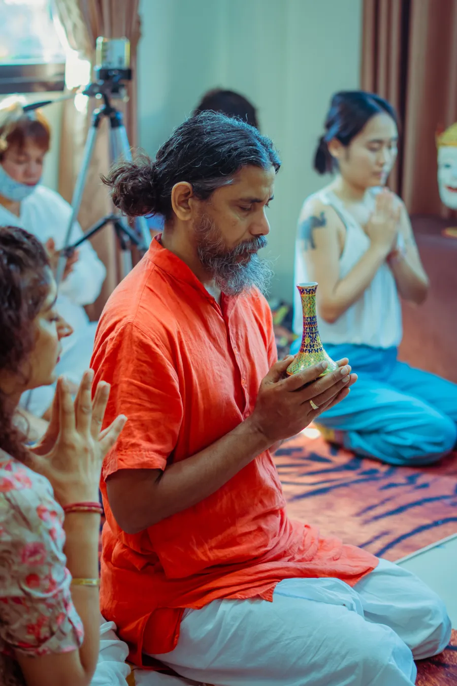 A teacher holding a sacred vessel during a meditation ceremony