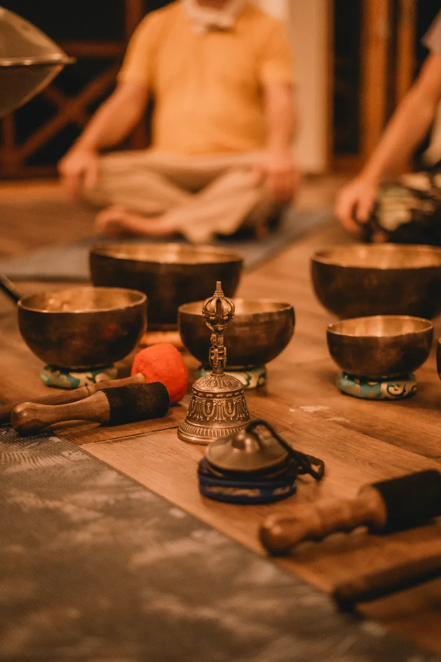 Tibetan singing bowls, a bell and tingsha laid out before seated students