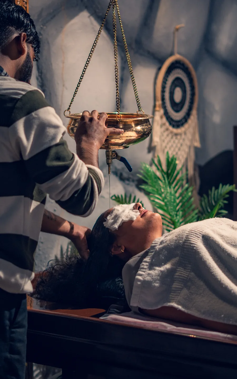 A therapist pouring warm oil during Shirodhara