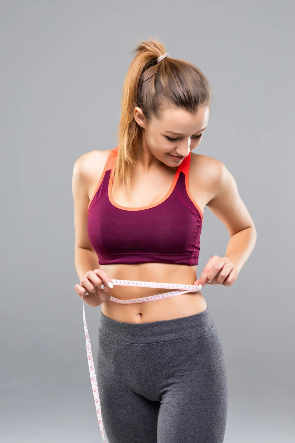 A woman measuring her waist with a tape